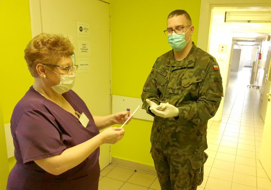 Żołnierze robią wymazy w mobilnym punkcie przy szpitalu razem z pracownikami laboratorium
